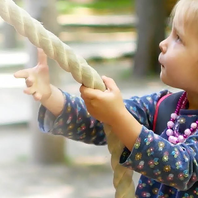 Young girl playing on a climbing rope